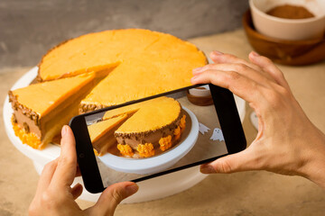Female Hands with phone taking pictures of Halloween cake. Pastry cook filming video blog