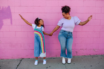 Mother and daughter in front of pink wall