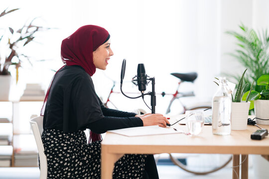 Smiling Arab woman recoding podcast and talking in mic