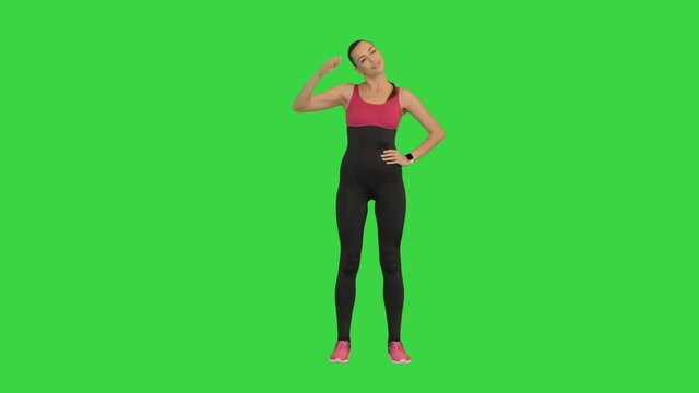 Caucasian woman athlete wearing black sportsbra warming up neck before workout on a Green Screen, Chroma Key.