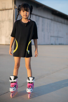 Asian girl playing rollerblades on a concrete patio