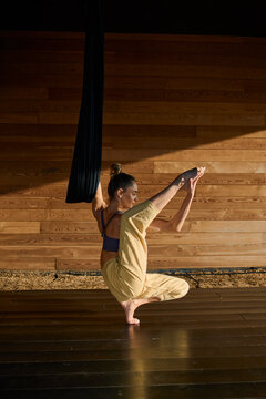 woman practicing aeral yoga on studio at sunset