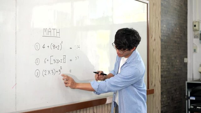 Educational concept a young smart male teacher explaining decision of hard math in a classroom