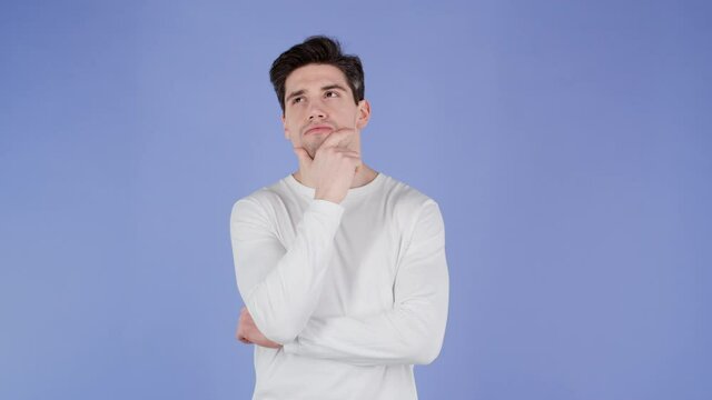 Young thinking pondering man having idea moment pointing finger up on violet studio background. Smiling happy guy showing eureka gesture, he found answer.