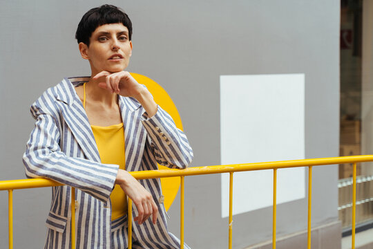 Stylish woman resting near yellow fence