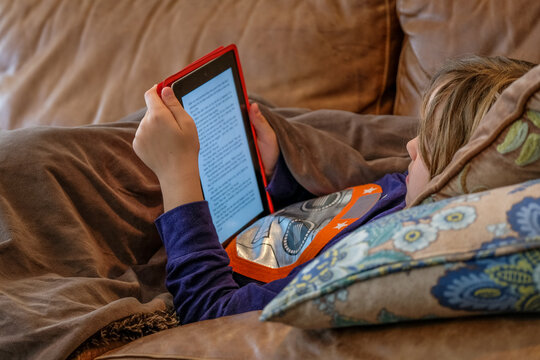Boy Reading An Ipad While Lying On A Couch