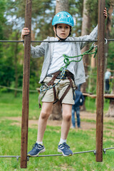 Cute, attractive boy moves on a metal obstacle. The boy holds his hands firmly so as not to fall