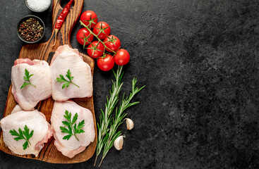 raw chicken thighs with spices and herbs on a stone background with a copy of the space for your text