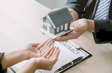 Fototapeta na wymiar Hand a real estate agent hold the home model, key and explain the business contract