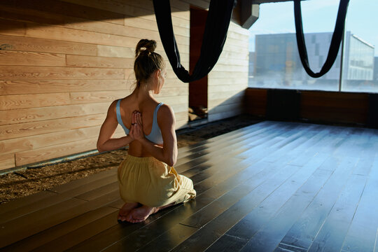 woman practicing aeral yoga on studio at sunset