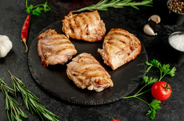 grilled skinless chicken thighs with spices and herbs on a stone background