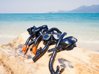 snorkels mask are on timber with the sand beach and sea background