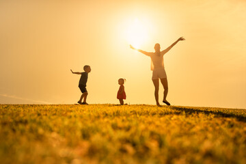 Happy family: mother, children son and daughter enjoying nature sunset

