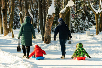 Parents pull on sleds children. A man and a woman sled their children. Winter walk concept. Winter...