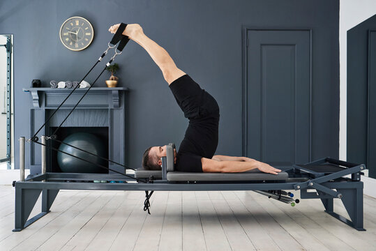 Man doing exercises on pilates reformer in gym