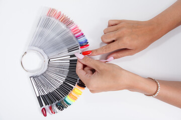 Female hands picking nail polish color from the palette