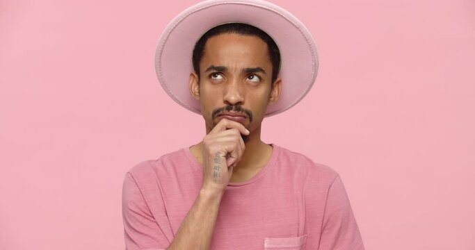 Young bearded man in pink hat thinking and have an idea isolated over pink