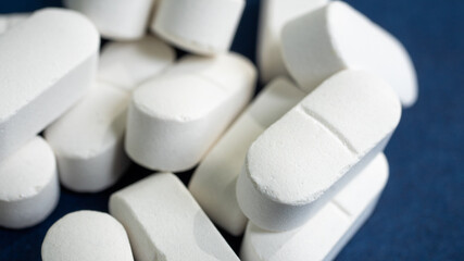 Amazing closeup of white generic medical pills, stacked together in a pile. Medical journals and...