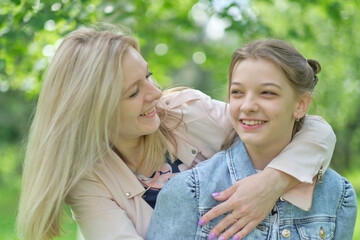 happy mother with her daughter hugging a teenager in the summer. Caring happy mother enjoy day with teenage girl child, laugh have fun. Mother giving her daughter advice.