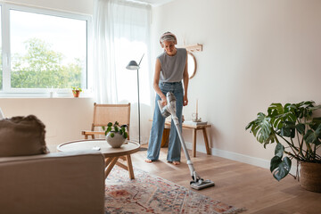 Mature housewife cleaning floor in living room