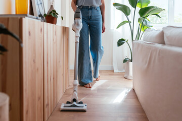 Crop woman cleaning floor behind couch