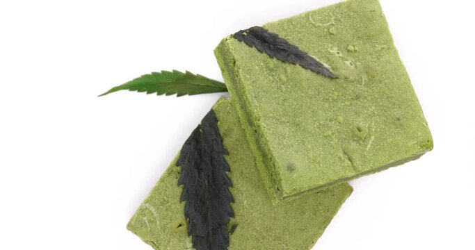 Tasty matcha cannabis white chocolate bars slowly revolving on white background.
