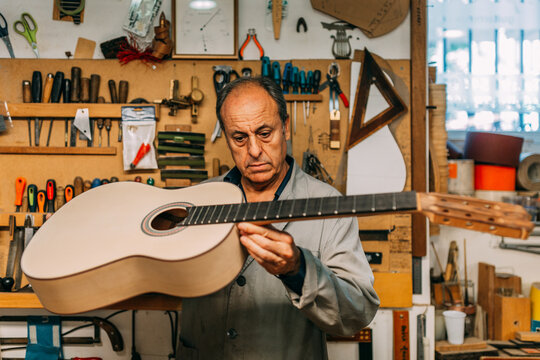 Senior luthier checking the finishing of a handcrafted spanish guitar