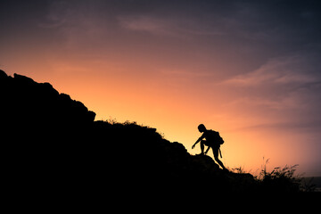 Hiker silhouette starting his climb up the mountain. Outdoor adventure, motivation and active sport...