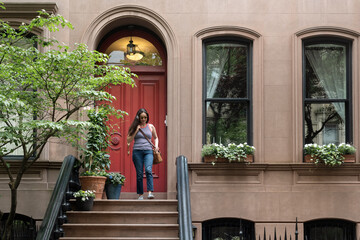 Woman leaving brownstone apartment building