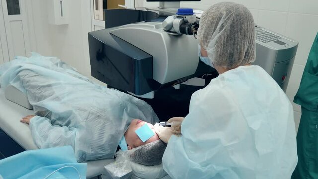 Doctor is looking into a microscope while operating patient's eye