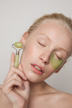 Model with green jade roller and under-eye patch