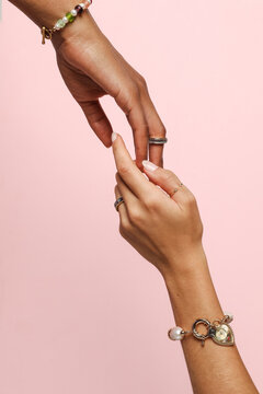 Two female hands with jewelry on holding each other