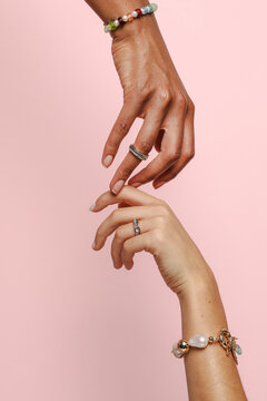 Two female hands with jewelry on holding each other