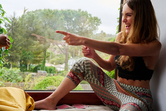 Laughing woman playing at cards with friend