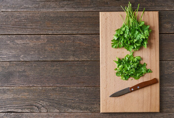 Fresh chopped green parsley leaves on a cutting board, top view.