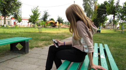A girl sitting on a bench in the phone