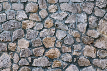 Texture of a stone wall. Part of old castle stone wall background. Gray stone siding with different sized stones.