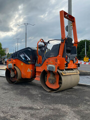 Orange powerful large new modern road roller for asphalt paving and road repair at construction site. Construction machinery