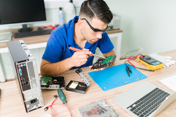 Male technician using a soldering iron on a pc component