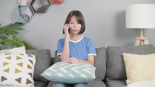 asian girl sit on sofa and use mobile phone in living room at home.
