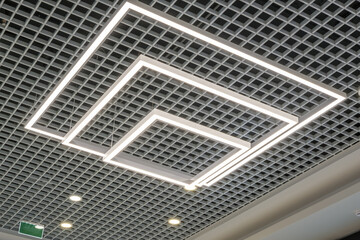 suspended and grid ceiling with halogen spots lamps and drywall construction in empty room in store...