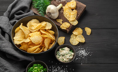 Potato chips, a beer snack on a black wooden background.