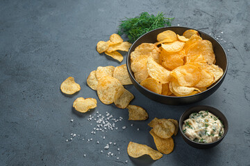 Potato chips, sauce, dill on a gray background.