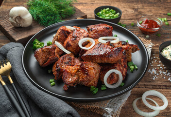 Grilled meat, barbecue, kebab with fresh herbs on a wooden background.