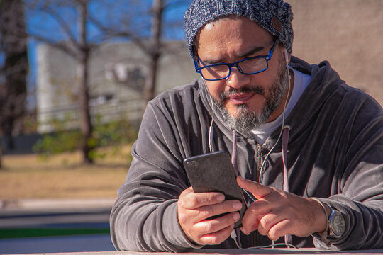 Latino listening to music on his smartphone