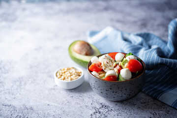 Cucumber tomato avocado mozzarella salad in a bowl