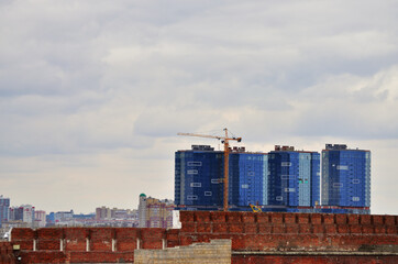 An old brick fence against the background of a new modern glass building under construction. Russia Kazan 24.04.2021. High quality photo