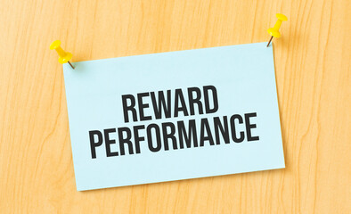 REWARD PERFORMANCE sign written on sticky note pinned on wooden wall
