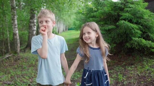A boy and a girl hold each other's hand and smile. A boy loves a girl. The girl fell in love with the boy. Children's friendship. Falling in love in childhood. Romantic children. Charming smile