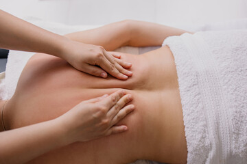 woman is lying on a back massage. Treating muscle pain. masseur kneads the client. Chiropractor at...